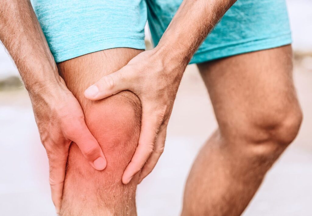 Man grabbing his knee because it's sprained or strained.