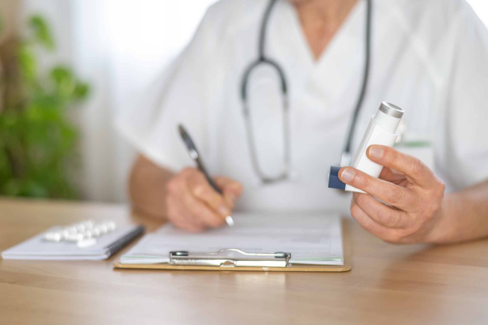 Allergist Doctor Holding An Asthma Inhaler And Writing A Prescription