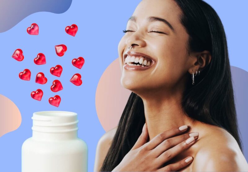 Woman smiling next to a bottle of heart shaped vitamins.